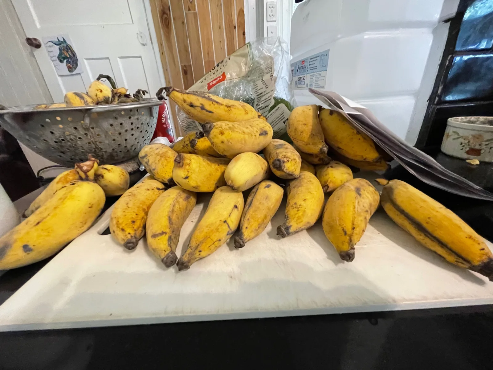 Ripe yellow bananas piled on a white cutting board.
